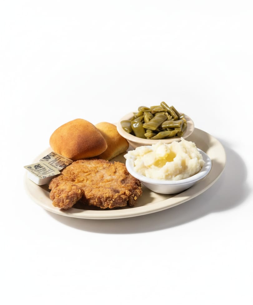 Fried pork chop with mashed potatoes, green beans, and dinner rolls on a plate.
