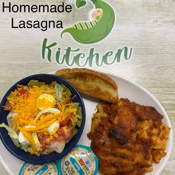 Homemade lasagna, a side salad with ranch dressing, and garlic bread on a white plate.