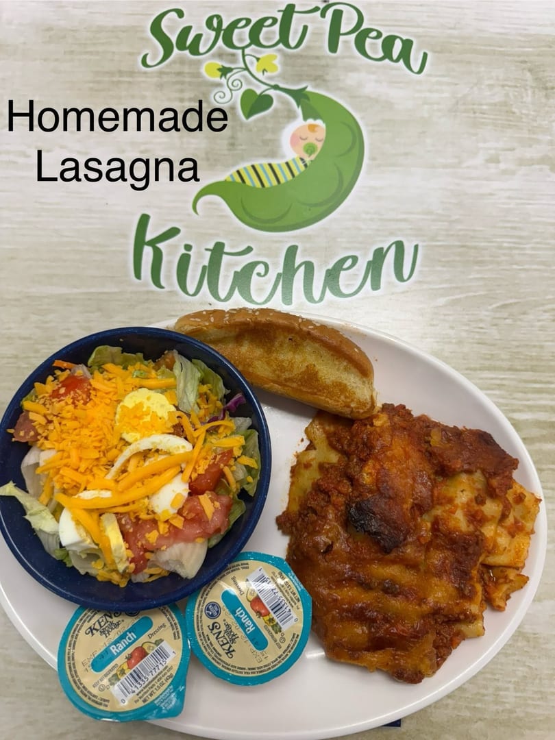 Homemade lasagna, a side salad with ranch dressing, and garlic bread on a white plate.