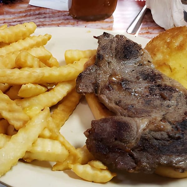 A plate of steak, crinkle-cut fries, and Texas toast, with a side of gravy.