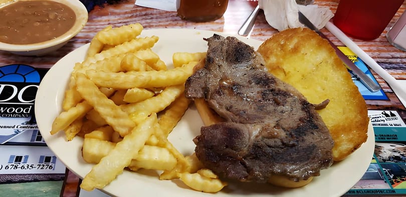 A plate of steak, crinkle-cut fries, and Texas toast, with a side of gravy.